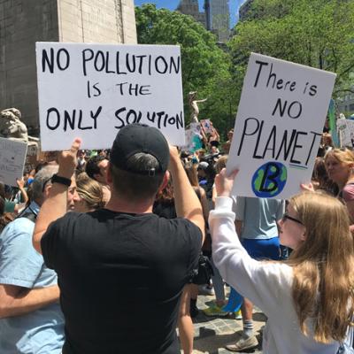 People holding signs at the Climate March 2019. The signs read, "No pollution is the only solution," and "there is no Planet B."