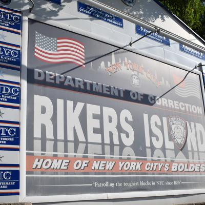 A sign which reads "Department of Correction, Rikers Island. Home of New York City's Boldest"