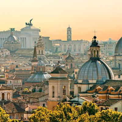 Spires and bell towers make up the skyline of Rome against a sunset