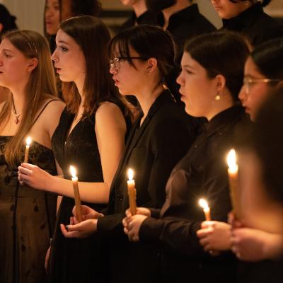 Teenagers in black clothes singing while holding candles