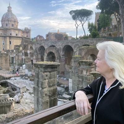 Woman stands at railing looking out over ancient city