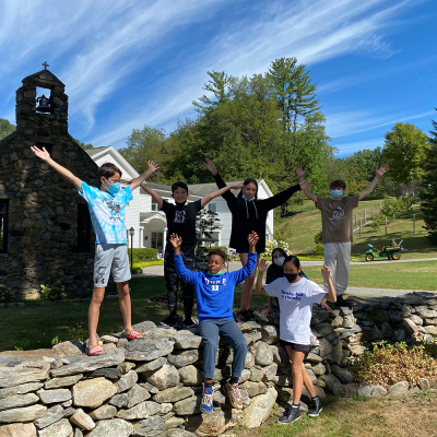 A group of kids posing on a stone wall at the Trinity Retreat Center