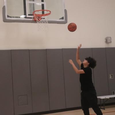 Child throws basketball to hoop in the Trinity Gym.