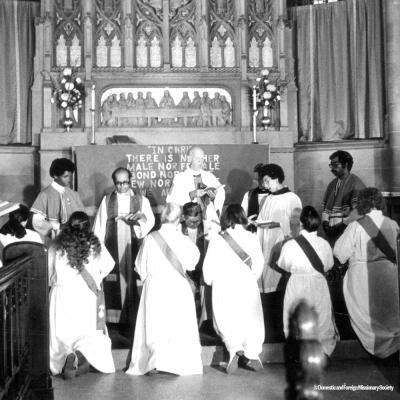 Women kneel at an altar during an ordination service